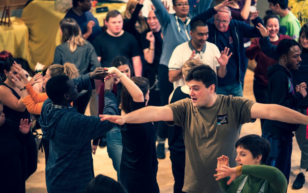 Group of people stretching out their arms in a drama workshop