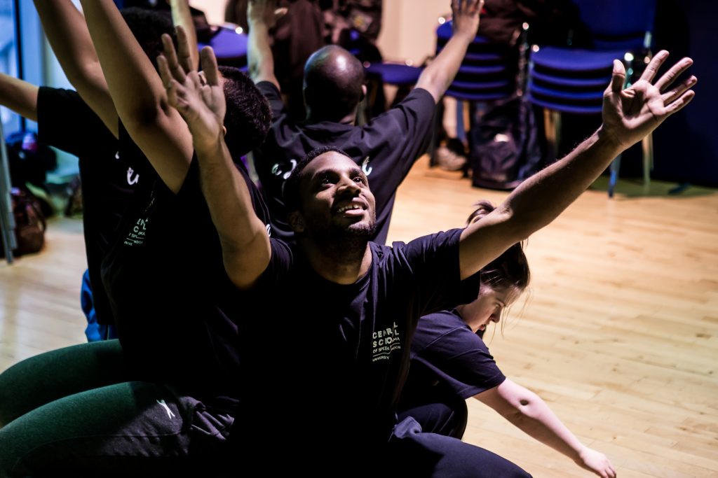 A group pf people huddle together with their arms in the air