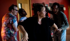 A woman leads a group in an exercise in which she contorts her face and body to look animalistic