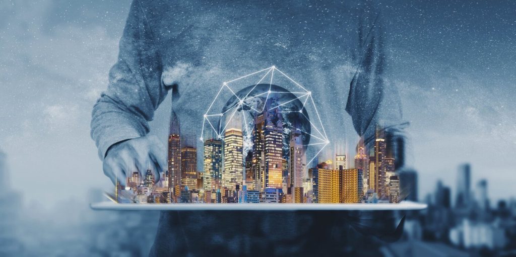 A blue cityscape. Behind which is the large torso of a man in a sweatshirt