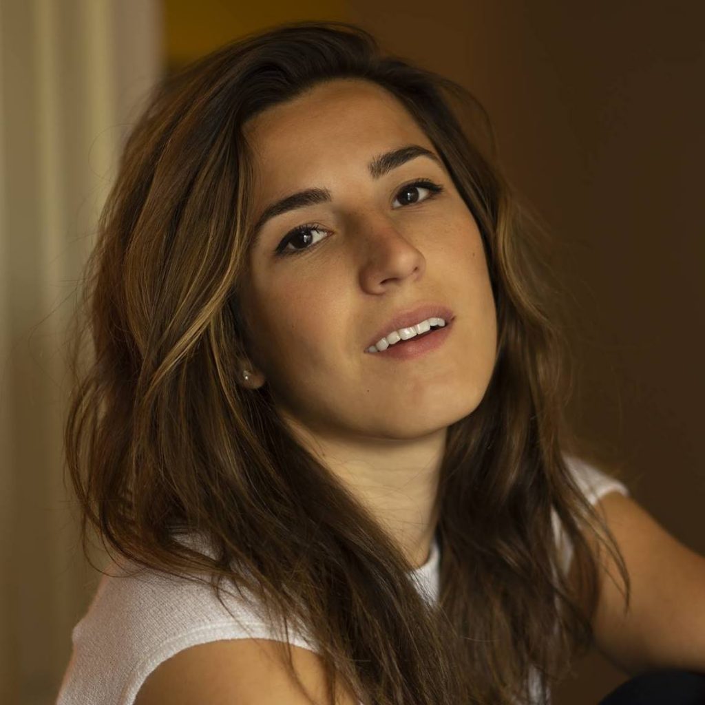 Eve-Lyne has mid-lenght brown hair and is looking at the camera with a slight smile.